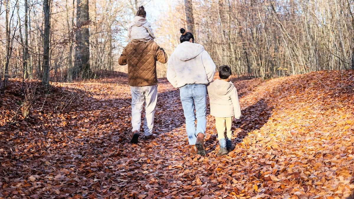 Family walking on a path in an autumn forest.